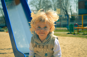 Small blond girl at playground on slide